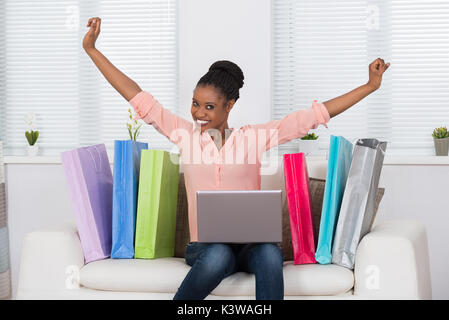 Giovane africana Excited donna mentre lo Shopping Online su Laptop Foto Stock