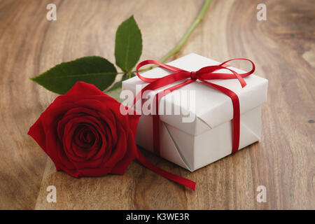 Red Rose con confezione regalo sul tavolo di legno Foto Stock