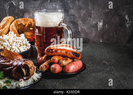 Selezione di cibo tradizionale tedesco Oktoberfest. La birra, cotta lo stinco di maiale, popcorn, assortimento di diverse salsicce, bretzels fatti in casa. Su un nero sto Foto Stock