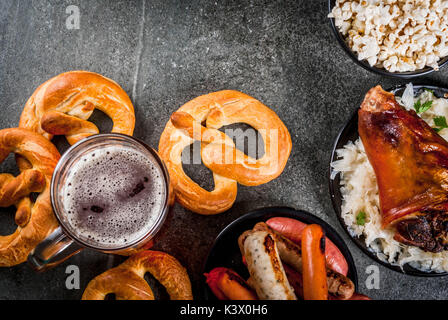 Selezione di cibo tradizionale tedesco Oktoberfest. La birra, cotta lo stinco di maiale, popcorn, assortimento di diverse salsicce, bretzels fatti in casa. Su un nero sto Foto Stock