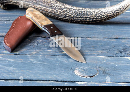 Coltello hunter e corno di cervo. Coltello con fodero in cuoio. Foto Stock