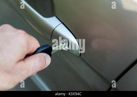 Mano d'uomo apre la portiera della macchina con una chiave. Foto Stock