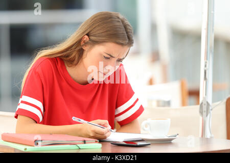 Unico confuso studente di lettura delle note seduto in un bar Foto Stock