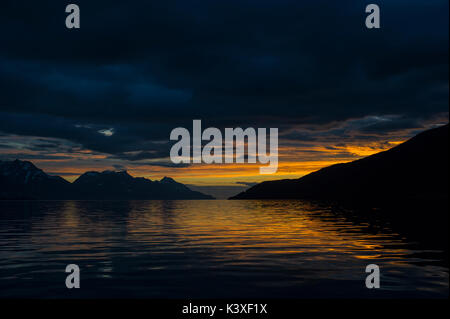 Sunrise riflessa nel mare in Lyngenfjord a nord del Circolo Polare Artico, Norvegia durante l'estate. Foto Stock