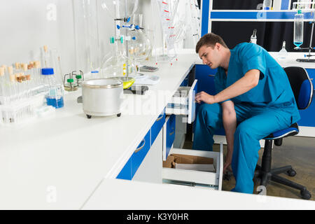 Scienziato in uniforme è alla ricerca di qualcosa in casi in un laboratorio. Assistenza sanitaria e il concetto di biotecnologia Foto Stock