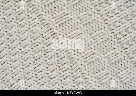 La tessitura di un beige maglione di close-up. Orientato diagonalmente pigtail sul tessuto a maglia Foto Stock