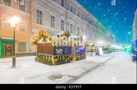 Decorato per il Natale e il nuovo anno coperto di neve street. Via centrale con edifici storici della città di Mosca Foto Stock