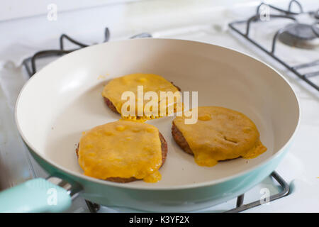 Tre veggie cheeseburger frittura sulla sommità della stufa Foto Stock