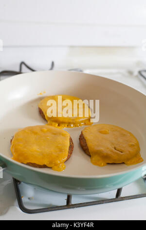 Tre veggie cheeseburger frittura sulla sommità della stufa Foto Stock