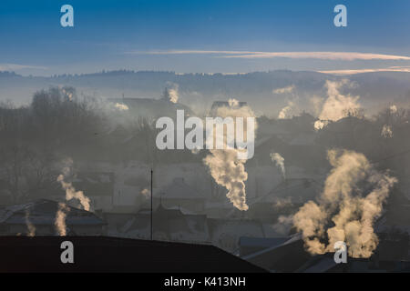 È molto freddo al mattino sunrise in città, comignoli fumanti. Inquinamento ambientale. Foto Stock