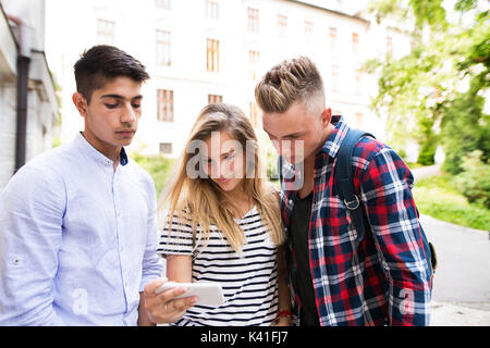 Un gruppo di studenti di fronte università tenendo selfie. Foto Stock