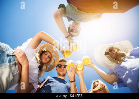 Una foto di gruppo di amici in piedi in cerchio con la birra nelle loro mani. Foto Stock