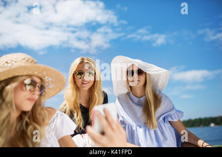 Una foto di tre giovani donne rilassante all'aria fresca presso il lago. Foto Stock