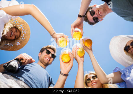 Una foto di gruppo di amici in piedi in cerchio con un litro di birra nelle loro mani e tostare per la loro amicizia. Foto Stock