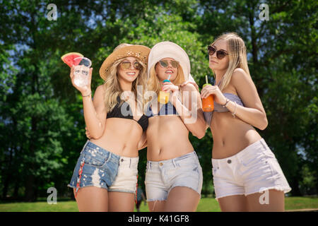 Una foto di giovani e belle donne in bikini in posa per la foto con drink esotici. Foto Stock