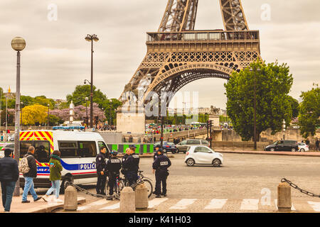 Parigi, Francia - 08 Maggio, 2017 : Polizia carrello viene parcheggiato in strada di fronte alla torre eiffel e accanto ad essa sono funzionari di polizia in bicicletta Foto Stock