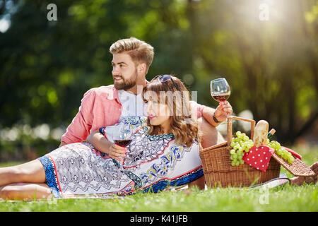 Una foto di una coppia giovane picnic al parco. Stanno bevendo vino e rilassante. Foto Stock