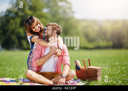 Una foto di una giovane coppia felice picnic al parco. Sono coccole e sorridente. Foto Stock