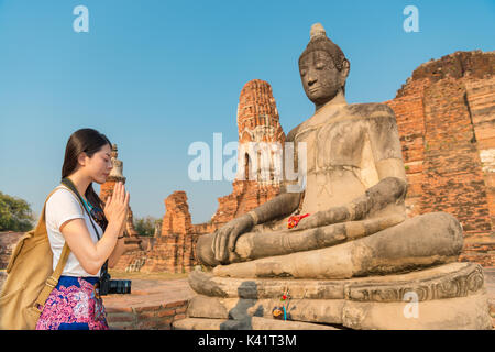 Bella dolce turista femminile pregando con il buddha sperando famiglia sana in Ayutthaya wat mahathat sui viaggi in Thailandia godetevi il buddhismo cultura. Foto Stock