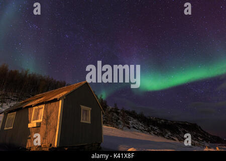 Northern Lights illumina la cabina in legno a Svensby Alpi Lyngen Tromsø Lapponia Norvegia Europa Foto Stock