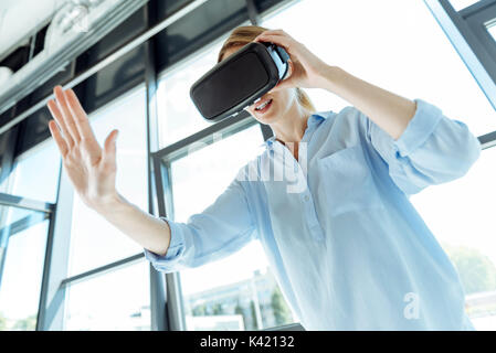 Giovane donna in cuffia VR stendendo la mano Foto Stock