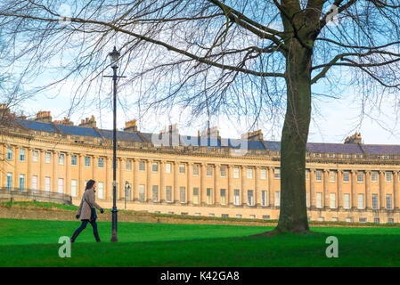 Bath Royal Crescent, sullo sfondo del Royal Crescent a Bath, Inghilterra, una donna cammina attraverso il Victoria Park nel centro della città, Regno Unito. Foto Stock