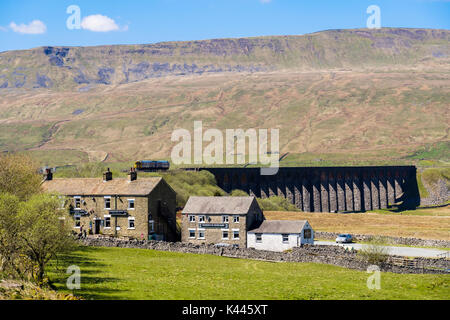 Station Inn Pub e fienile a castello con il treno diesel incrocio viadotto Ribblehead sotto Whernside. Yorkshire Dales National Park North Yorkshire England Regno Unito Foto Stock