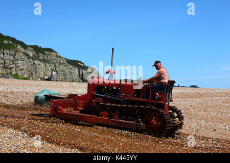 Guida del pescatore di bulldozer utilizzato per spingere barche da pesca fino spiaggia ghiaiosa, Hastings, East Sussex, Inghilterra Foto Stock