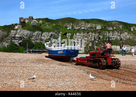 Fisherman utilizzando bulldozer per spingere la barca da pesca fino spiaggia ghiaiosa, Hastings, East Sussex, Inghilterra Foto Stock