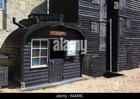 Mezza sovrano Cottage (realizzato da metà di un vecchio legno barca da pesca) e storiche di legno nero negozi netto, Hastings, East Sussex, Inghilterra Foto Stock