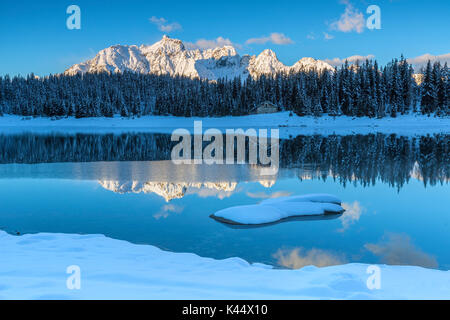 Cabina in legno circondata da vette innevate e boschi si riflette nel lago Palù all'alba Malenco Valley Valtellina Lombardia Italia Europa Foto Stock