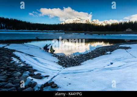 Gli escursionisti ammirare il lago Palù mentre la molla del disgelo si scioglie il ghiaccio Provincia di Sondrio Malenco Valley Valtellina Lombardia Italia Europa Foto Stock