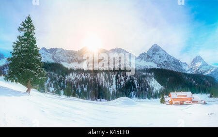 Vista panoramica di un villaggio alpino coperto di neve e circondato da alte cime delle Alpi e i loro sempreverdi foreste di abeti, situato in Foto Stock