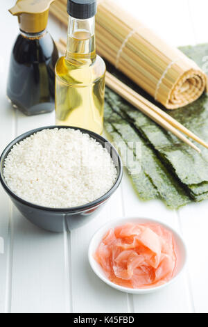 Il sushi ingredienti sul tavolo bianco. Riso, lo zenzero, la salsa di soia, aceto e nori fogli. Foto Stock