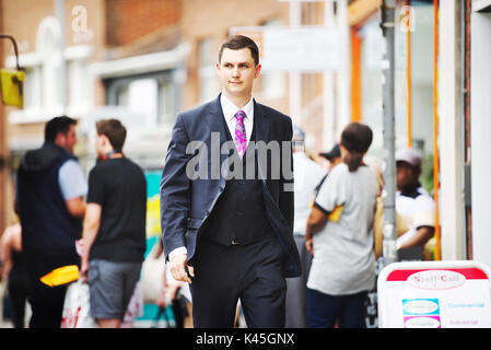 Bianco giovane imprenditore inglese passeggiate attraverso un trafficato centro cittadino con il pubblico in generale in background e vicino alla zona dello shopping Foto Stock