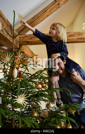 Uomo e bambino decorare l'albero di Natale Foto Stock