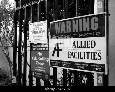 Strutture alleate questi locali sono protetti cartello segnaletico montato su cancelli in ferro, ingresso al parco industriale Foto Stock