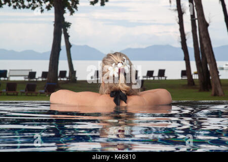 Donna in piscina in Thailandia guardando il mare.donna rilassante vicino alla spiaggia in krabi.bianco plumeria fiore su una donna capelli.Mare delle Andamane Foto Stock