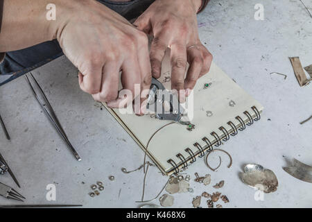 Gli occhi di uccello vista delle mani di un gioielliere femmina lavorando sul suo posto di lavoro. Foto Stock