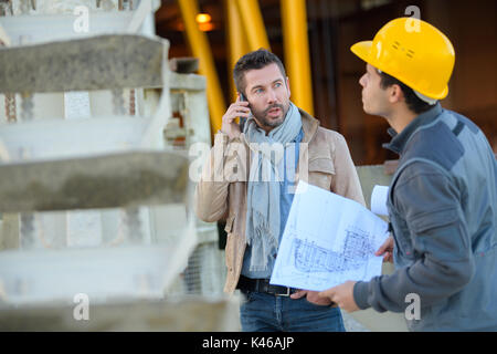 Due maschi ingegneri industriali guardando discussone piani di disegno Foto Stock