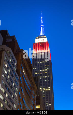 Empire State Building di notte che mostra i colori della bandiera americana, rosso, bianco e blu Foto Stock