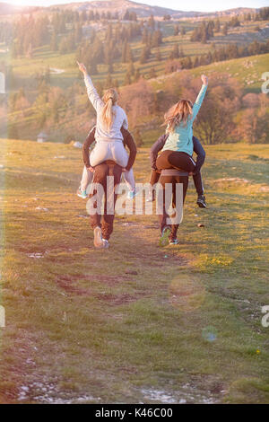 Gruppo di amici adolescenti avente Piggyback passeggiate nel paesaggio autunnale Foto Stock