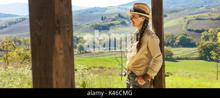 Alla scoperta di magiche vedute della Toscana. sorridente donna attiva escursionista in hat in Toscana guardando in lontananza Foto Stock