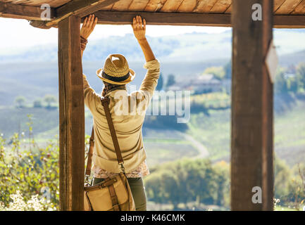 Alla scoperta di magiche vedute della Toscana. Visto da dietro la donna escursionista in hat in Toscana guardando in lontananza e godere un paesaggio mentre Foto Stock