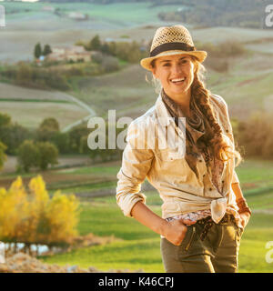 Alla scoperta di magiche vedute della Toscana. Ritratto di donna avventura escursionista in hat godendo di sera in Toscana Foto Stock
