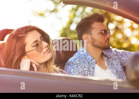 Coppia giovane la guida lungo la strada di campagna in Open Top Car Foto Stock