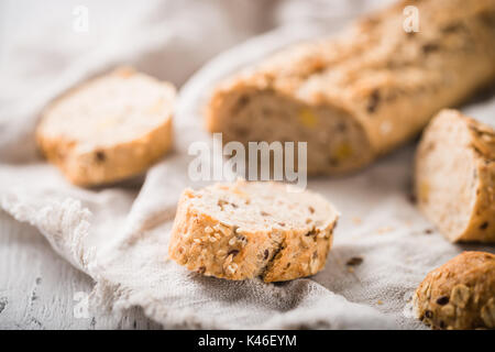 Fresco, sano grano intero fette di segale su tela e tavola in legno rustico, baguette close up. Panificio e concetto di negozi di generi alimentari Foto Stock