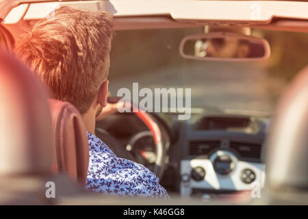 Coppia giovane la guida lungo la strada di campagna in Open Top Car Foto Stock
