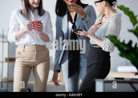 Ritagliato colpo di giovani imprenditrici multietnica di bere il caffè e a parlare in ufficio Foto Stock