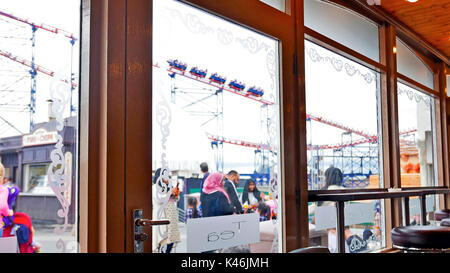 La Big One roller coaster visto attraverso le finestre e la porta di un coffee shop a Blackpool Pleasure Beach Foto Stock